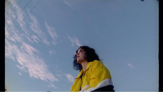 A girl standing in a colourful jacket under the sky