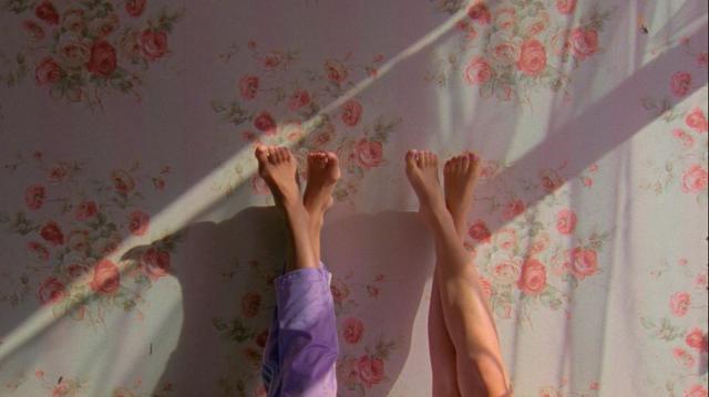 Two pairs of feet leaned against the floral wallpaper