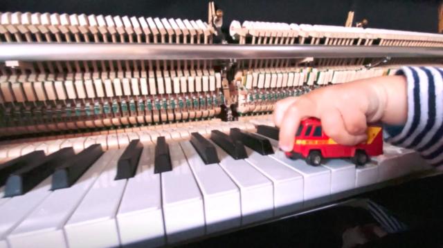 Kids hand holding a toy on a piano