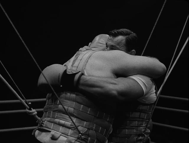 Two men hugging each other in a box ring